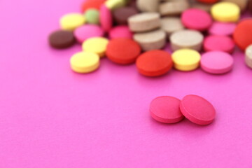 Obraz na płótnie Canvas Two pink pills lie on a pink background and a bunch of different pills.