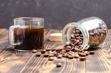 Cup of coffee and beans are scattered from a glass jar.