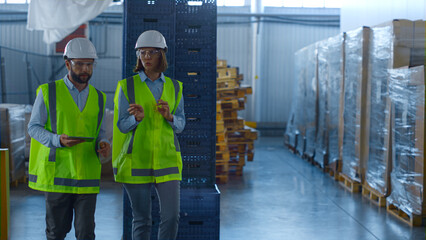 Two uniformed warehouse workers discussing manufacture production inspecting