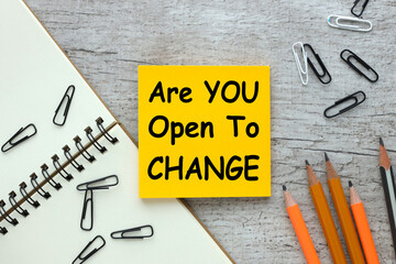 Are you Open to change. sticky note with text on wooden background and other supplies