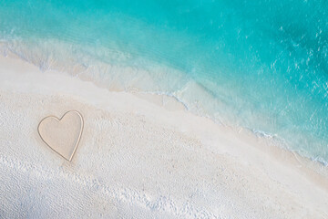 Perfect drawing of heart shape in soft sand beautiful seascape background. Romantic Valentine's day or love beach scene, top aerial view. Romance, honeymoon in vacation, summer travel. Idyllic nature