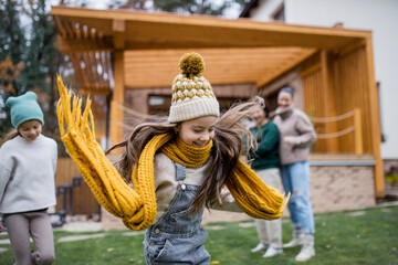 Two happy sisters with mother and grandmother playing and running outdoors in garden in autumn