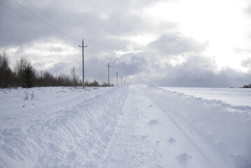 A deserted country road through snow-covered fields.