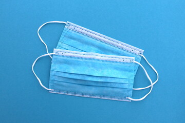 Two medical masks lie on a blue background.