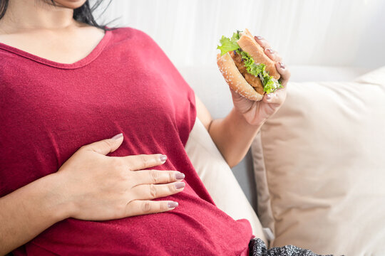 woman having stomachache or flatulence after eating burger,   hand holding her abdominal