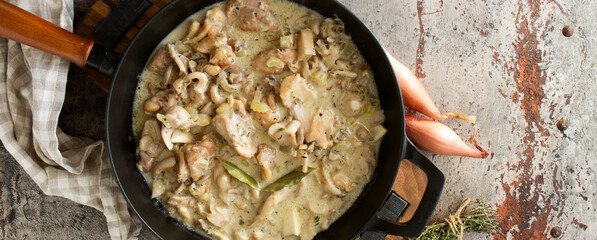 pan with chicken fricassee with mushrooms on the table
