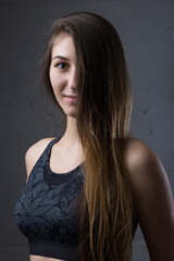 Naklejka premium Portrait of a slender athletic young girl against a concrete wall in a fashionable apartment interior.