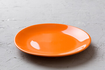 Perspective view of empty orange plate on cement background. Empty space for your design
