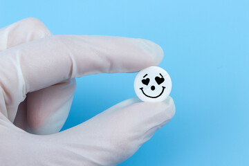 Pill with heart eyes in hands in medical gloves on a blue background. Viagra concept