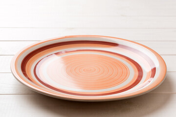 Perspective view of empty orange plate on wooden background. Empty space for your design