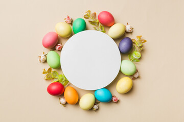 round frame multicolored Easter eggs with white blank paper on a brown background, close-up, space for text, blank for design, selective focus, tinted image