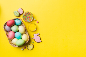 Colorful easter cookies in basket with Multi colors Easter eggs on colored background . Pastel color Easter eggs. holiday concept with copy space