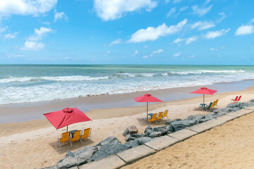 Sunshades and chairs on the sand of a beautiful tourist beach on a sunny day. Boa Viagem beach in Recife, PE, Brazil.
