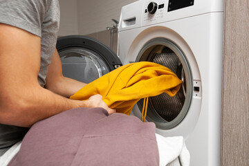 Man loading the washer dryer with clothes