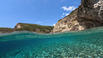 Underwater split photo of natural exotic island rocky bay with turquoise crystal clear sea and small caves