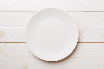 Top view of empty light plate on wooden background. Empty space for your design