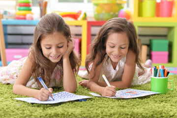 Two cute little girls drawing with pencils