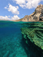 Fototapeta premium Underwater split photo of natural exotic island rocky bay with turquoise crystal clear sea and small caves