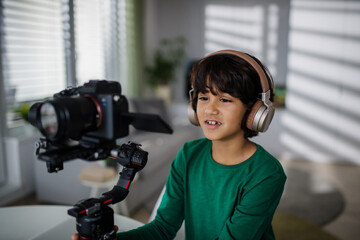 Happy multiracial boy cameraman amateur with headphones at home.