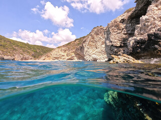 Obraz premium Underwater split photo of beautiful paradise pebble rocky bay of Kaladi with turquoise crystal clear sea and small caves, Kythira island, Ionian, Greece