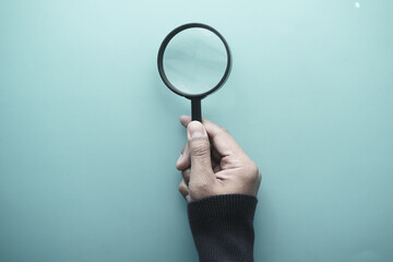 hand holding magnifying glass against white 