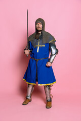 Full-length portrait of serious looking man, brtutal medieval warrior or knight in protective...