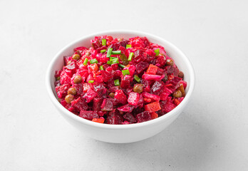 Salad vinaigrette with boiled vegetables, sauerkraut, cucumbers and peas on a light background.