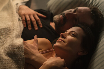 Sad mature man feeling guilty, thinking about cheating his wife, while his wife is snuggling to him.