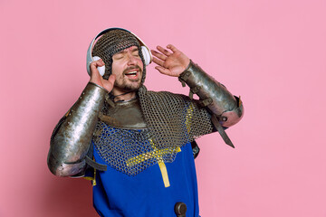 Half-length portrait of man, medieval warrior or knight listening to music in headphones with...
