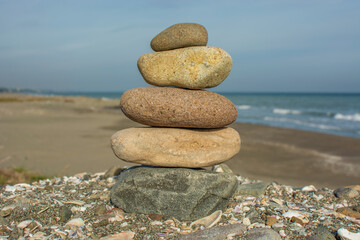 Pyramid of sea stones on the seashore at the pebble beach. Concept of harmony and balance.