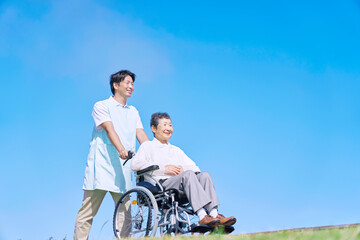 介護士と車椅子に乗る高齢者　屋外