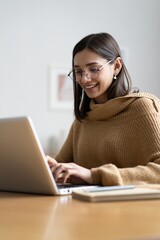 Smiling woman with laptop in home office. - obrazy, fototapety, plakaty