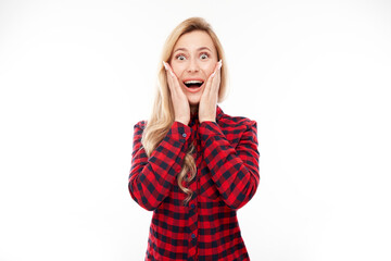 Fototapeta premium Shocked blond girl looks surprised holding head with hands on white studio background with copy space
