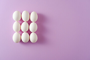 nine white eggs on purple background, abstract easter concept