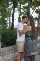 Fototapeta premium Loving couple kissing and hug each other on a walk in the city park in the summer weekend