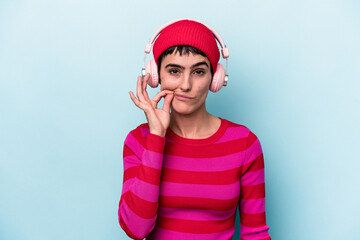Young caucasian woman listening to music isolated on background with fingers on lips keeping a secret.