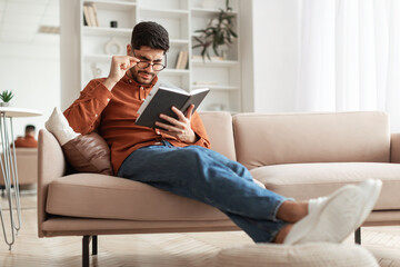 Obraz premium Focused Arab man in glasses trying to read book
