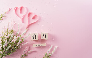 Happy Women's Day decoration concept made from flower, paper heart and wooden calendar on pink pastel background.
