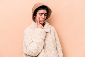 Young caucasian woman isolated on beige background crying, unhappy with something, agony and...
