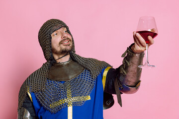 Half-length portrait of man, medieval warrior or knight in protective chain armor rising glass of...