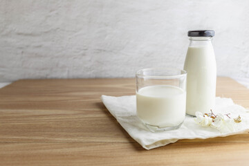 Milk bottle and glass of milk on wooden table in morning
