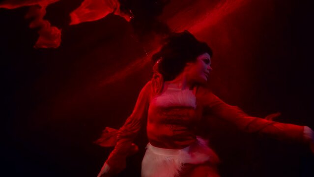 sexy excited woman is drowning in red water of river or lake, underwater mysterious shot