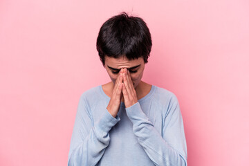 Young caucasian woman isolated on pink background praying, showing devotion, religious person...