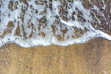 Ocean waves foam on the sand very close