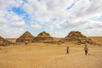 People walking near near Pyramids of Queens, part of the Ancient Egyptian Pyramids of Giza complex,...