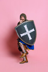Full-length portrait of scary man, medieval warrior or knight in armor hiding himself behind a...