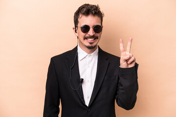 Young bodyguard caucasian man isolated on beige background showing number two with fingers.