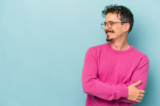 Young caucasian man isolated on blue background smiling confident with crossed arms.