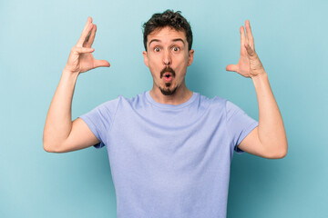 Young caucasian man isolated on blue background celebrating a victory or success, he is surprised and shocked.