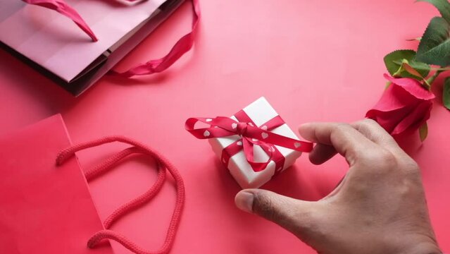 Top view of gift box and rose flower on red background 